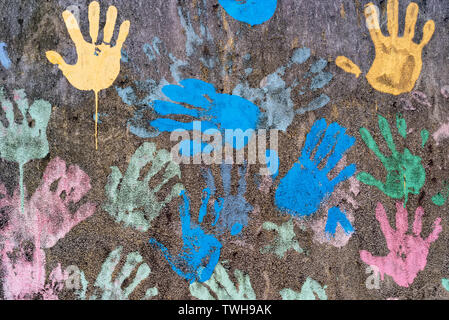 Dark background with colorful handprints symbolising interracial friendship Stock Photo