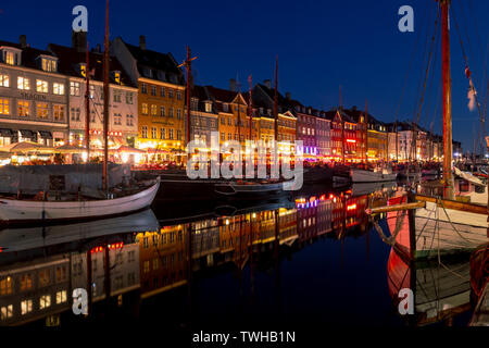 Copenhagen, Denmark: April 18, 2019: Illuminated houses and ships at Nyhavn district at night, an old canal and entertainment zone in Copenhagen Stock Photo