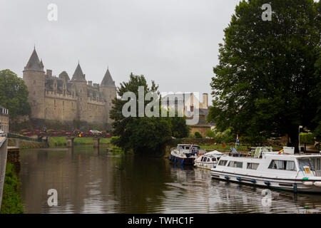 Josselin castle on a rainy day as seen from the Oust river. Boats on a side Stock Photo