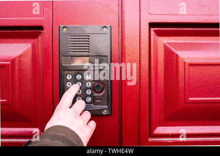 Male hand presses a button on doorbell and intercom. Stock Photo