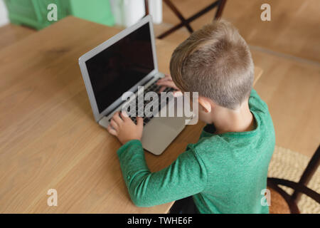 Cute boy using laptop at dining table in a comfortable home Stock Photo