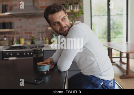 Man with coffee cup looking away at dining table Stock Photo