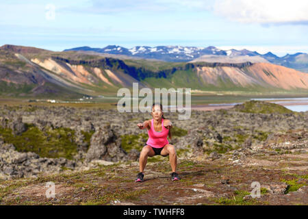 Fitness girl exercising outdoors doing jump squat in amazing nature landscape. Fit female woman athlete cross-training outside. Image from Iceland. Stock Photo