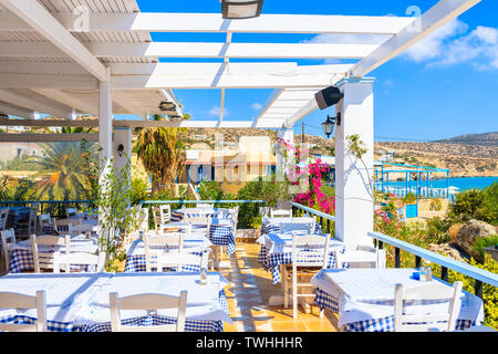 Terrace with tables in traditional Greek tavern decorated with flowers in Ammopi village on Karpathos island, Greece Stock Photo