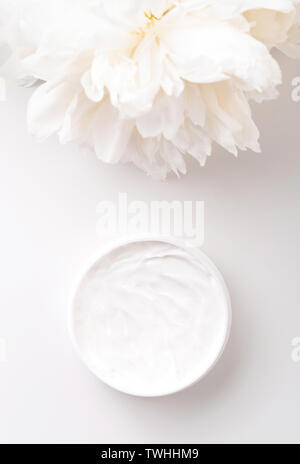 White peony and mockup face and body cream on white background. Cosmetics concept. Flat lay. Stock Photo