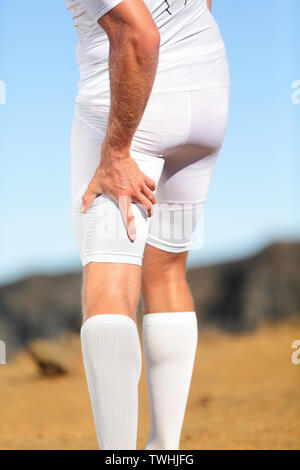 Running sports injury. Pulled hamstring muscle, muscle strain or muscle cramp in back thigh leg of man running outdoors. Stock Photo