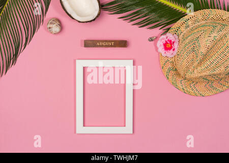 Stylish summer composition with photo frame, green leaves, hat and seashells on a pink pastel background. Artwork mockup with copy space Stock Photo