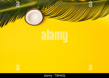 Flat lay coconut and palm leaves on yellow color background Stock Photo