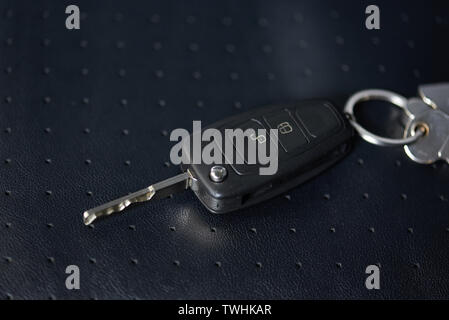Close-up of car keys lay on dark black leather background Stock Photo