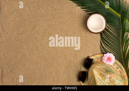 Beach theme on the sand background. Palm leaves, coconut, hat on the sand. Top view. Stock Photo