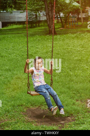 Asian girl on a swing at a park. Filipina kid. Stock Photo