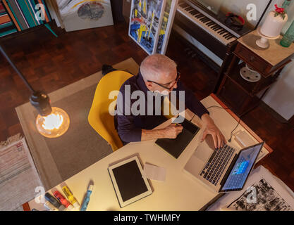 Middle aged man using computer in his art studio and drawing on his tablet Stock Photo
