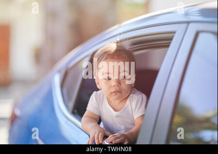 Travel on car theme. Small baby girl looking out from window side view Stock Photo