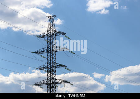 High voltage power line supports with electrical wires on background of blue sky with white clouds. Electricity transmission lines, power supply Stock Photo