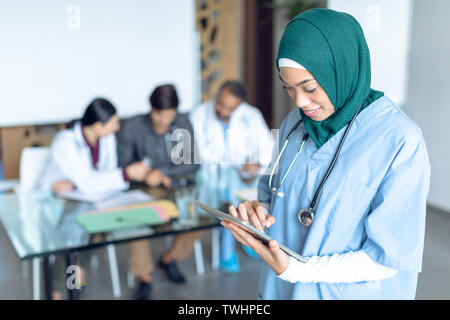 Happy female surgeon in hijab using digital tablet in the hospital Stock Photo