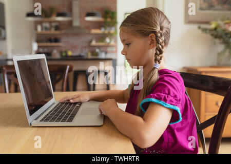 Cute girl using laptop on dining table in a comfortable home Stock Photo