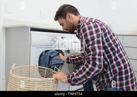 Man putting dirty clothes into the washing machine in a comfortable home Stock Photo