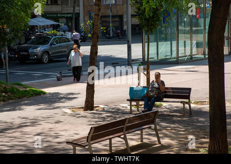 Barcelona, Spain - 27th July 2017 - Old lady with cigarette sitting on a bench in Barcelona Spain Stock Photo