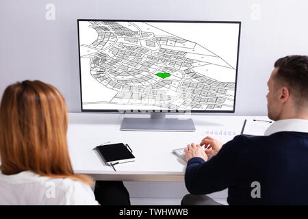 Close-up Of A Businesspeople Analyzing Cadastre Map On Computer In The Office Stock Photo