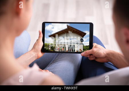 Close-up Of A Couple Looking At New House On Tablet Stock Photo