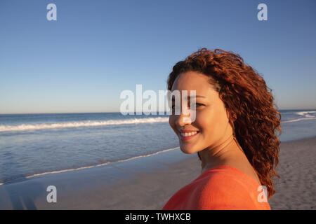 Beautiful happy woman looking at camera on beach in the sunshine Stock Photo
