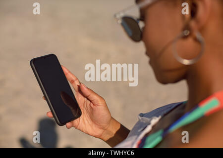 Woman using mobile phone at beach in the sunshine Stock Photo