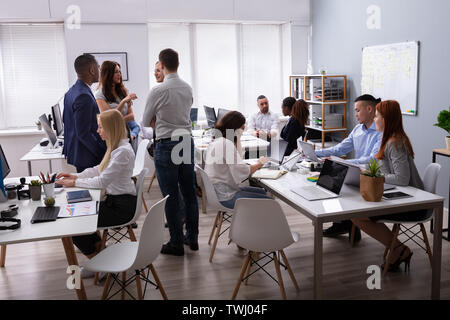 Group Of Businesspeople Discussing Together With His Colleague Working In The Office Stock Photo