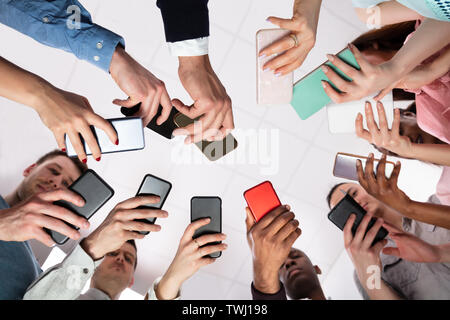 Group Of People Standing In Circle Using Smartphone Stock Photo