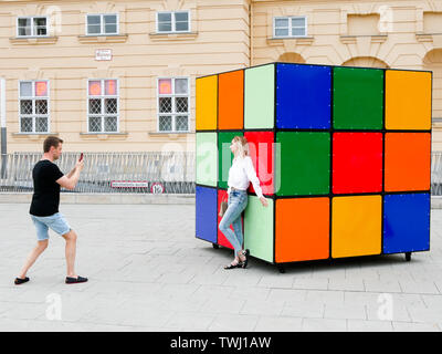 a couple taking a picture of a sculpture of Rubik's cube in the museums quartier in vienna Austria during the celebration of europride 2019 Stock Photo