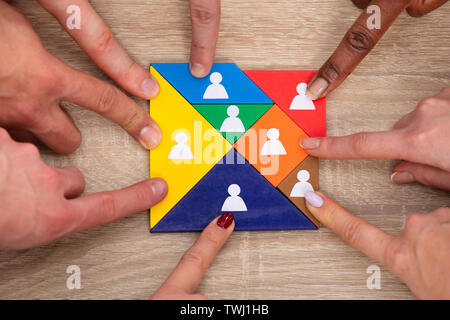 High Angle View Of Group Of People's Hand On Colorful Tangram Puzzle Blocks Stock Photo
