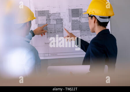 Architects discussing over blueprint on glass board in a modern office Stock Photo
