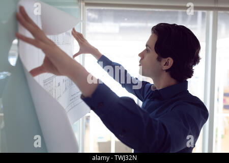 Male architect looking at blueprint in office Stock Photo