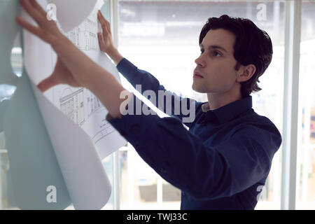 Male architect looking at blueprint in office Stock Photo