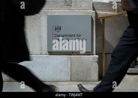 Pedestrians walk past the Department for International Trade sign outside the governmental department's building in London, UK. Stock Photo