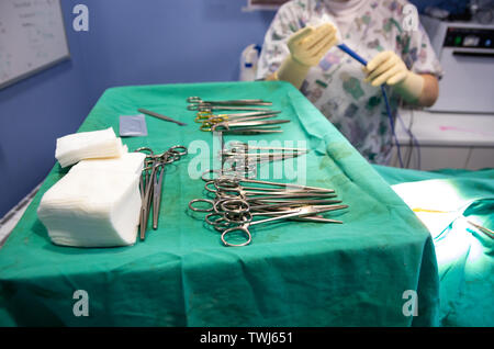 Surgical material in a sterile camp and the veterinarian preparing the electric scalpel in background Stock Photo