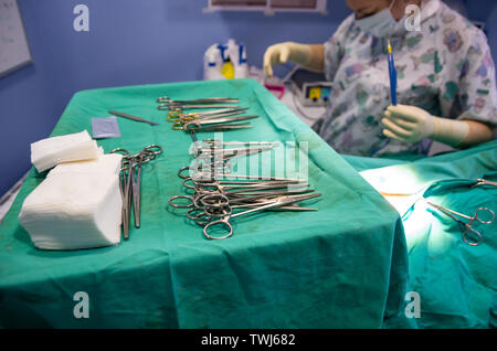 Surgical material in a sterile camp and the veterinarian preparing the electric scalpel in background Stock Photo