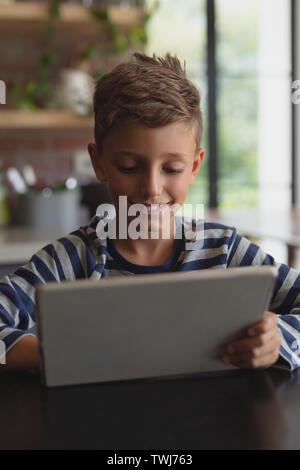 Boy using digital tablet at table in kitchen at home Stock Photo