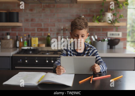 Boy using digital tablet at table in kitchen at home Stock Photo