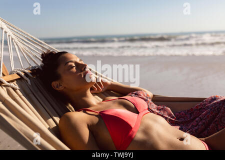 Woman in bikini sleeping in a hammock on the beach Stock Photo