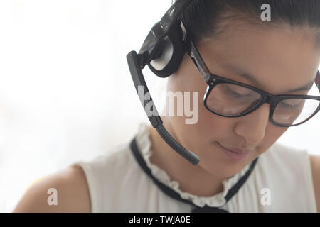 Female customer service executive with headset looking down in a modern office Stock Photo