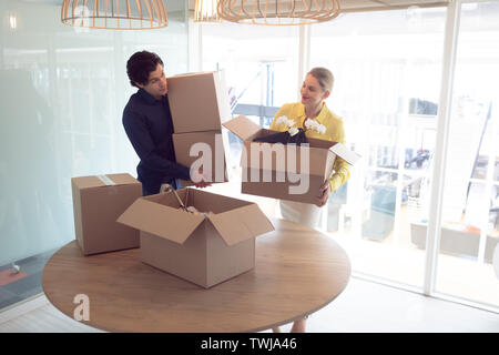 Male and female executives holding cardboard boxes in office Stock Photo