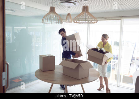 Male and female executives holding cardboard boxes in office Stock Photo
