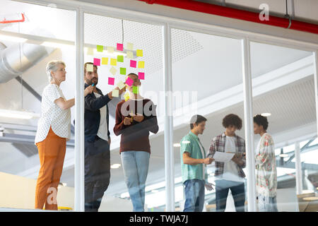 Business people discussing over sticky notes in the office Stock Photo