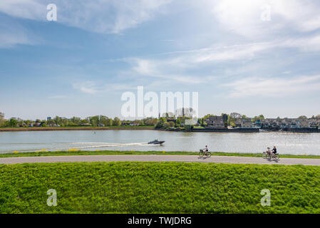 Capelle aan den IJsel, Rotterdam, Netherlands - April 22, 2019 : People cycling by the IJsel canal in the afternoon on a sunny day Stock Photo