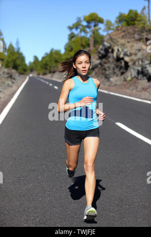 Running woman - female runner jogging outdoors on road training