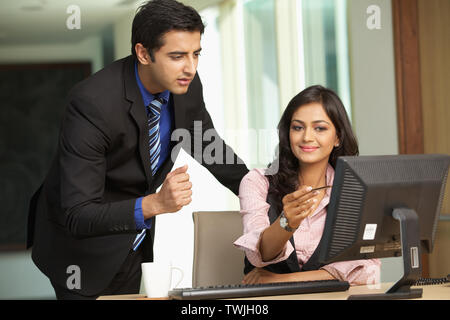 Two business executives working on a desktop pc in an office Stock Photo