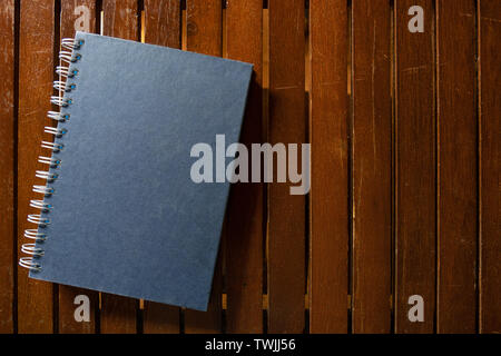 Dark blue closed hardcover book on wooden table. Top view with copy space Stock Photo