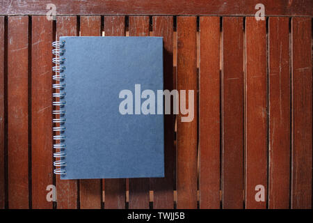 Dark blue closed hardcover book on wooden table. Top view with copy space Stock Photo