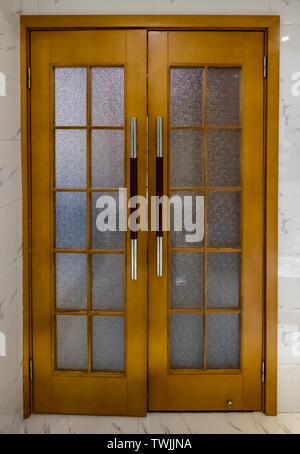 Wooden door with glass and handle on marble wall Stock Photo