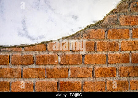 Weathered cracked orange bricks with plaster background Stock Photo